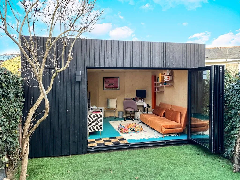 Dark-clad garden room with an open glazed front and furnished interior